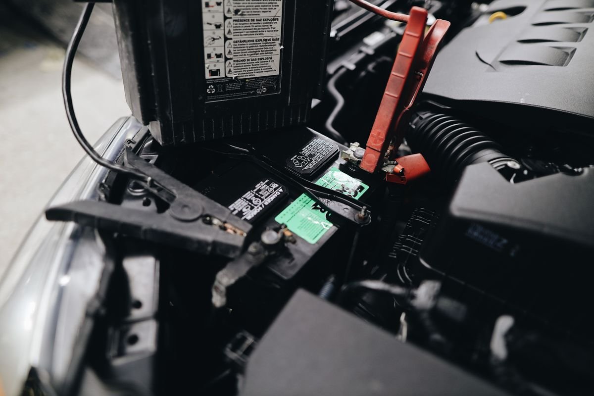 Portable car battery jump starter connected to a vehicle engine bay