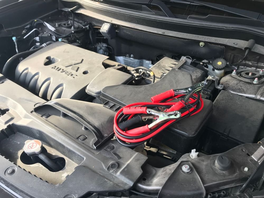 Jumper cables connected to a car engine, representing a portable jump starter in use