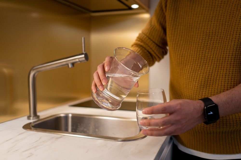 Hand pouring filtered water into a clear glass