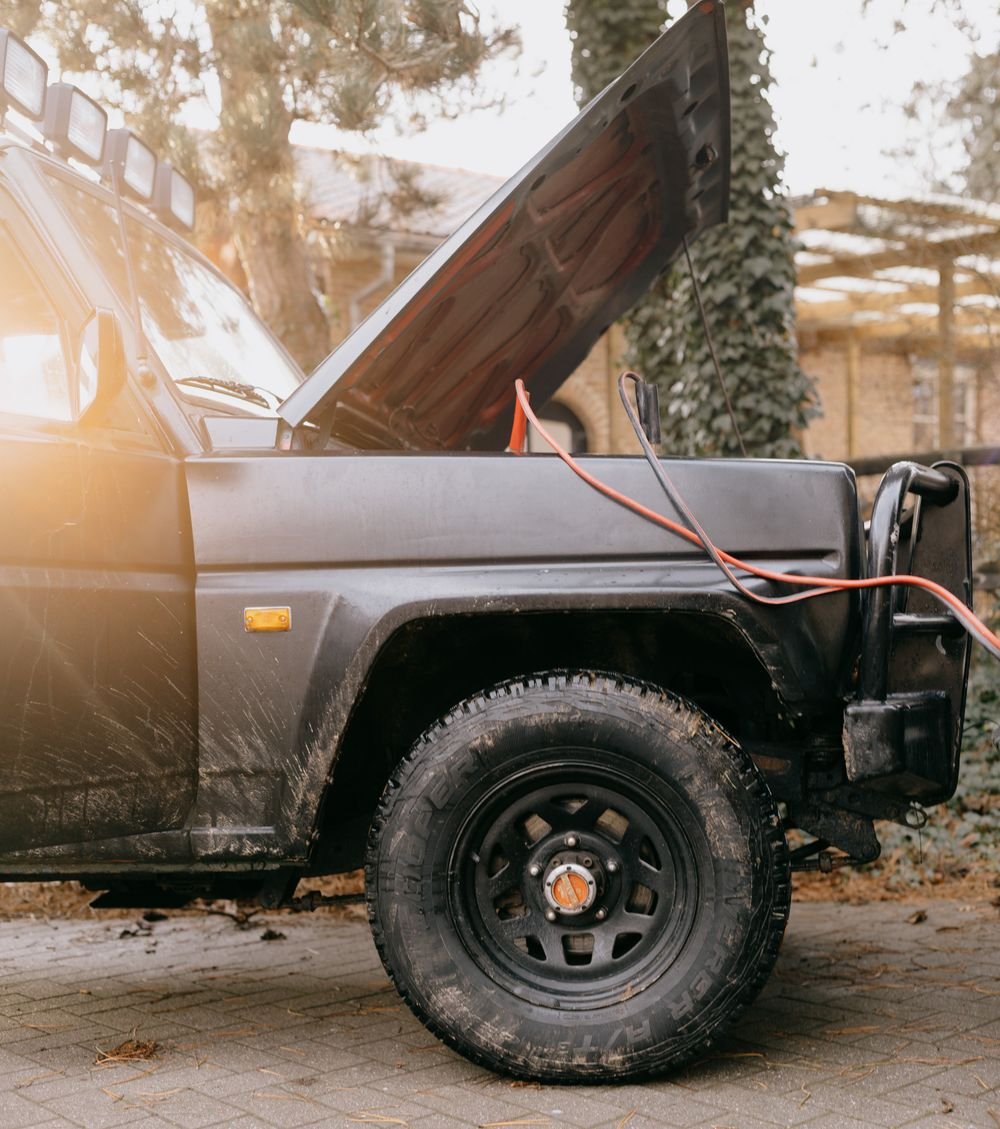SUV with hood open and jumper cables attached outdoors